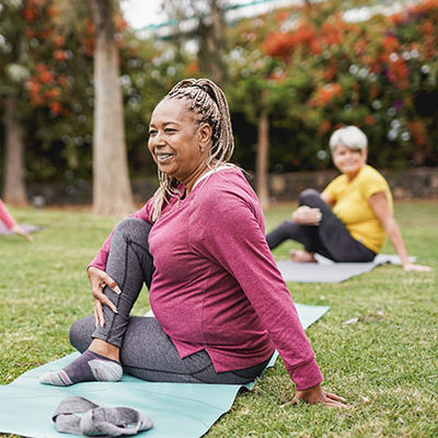 perimenopausal woman of color doing yoga in a park