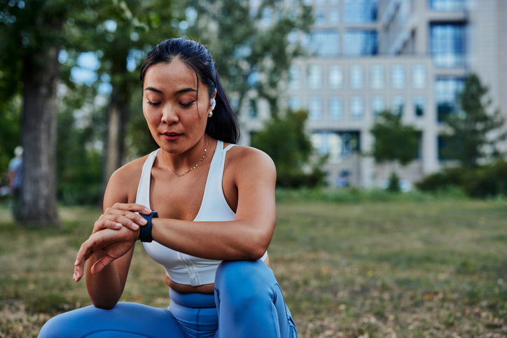 asian woman checking her smart watch stats while exercising